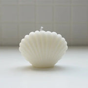 Shell-shaped candle on a light surface with a neutral background