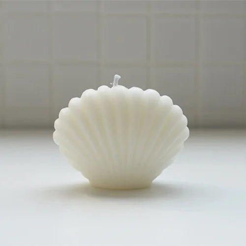 Shell-shaped candle on a light surface with a neutral background