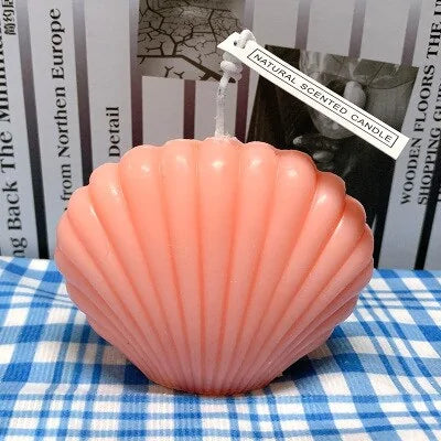 Pink shell-shaped candle on a blue and white checkered tablecloth with a blurred background.