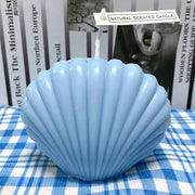 Blue shell-shaped candle on a checkered tablecloth with books in the background