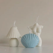 Light blue shell-shaped candle, white lamp, and mannequin on a neutral background